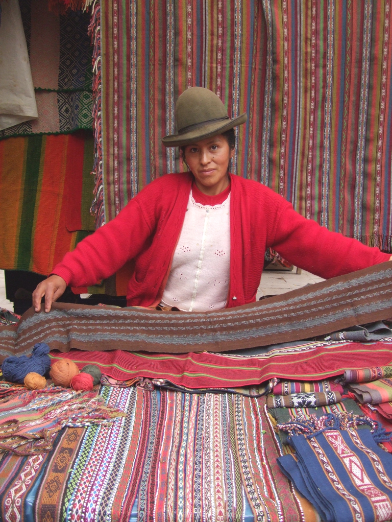 Artisan shows alpaca wool scarf in Pisaq market